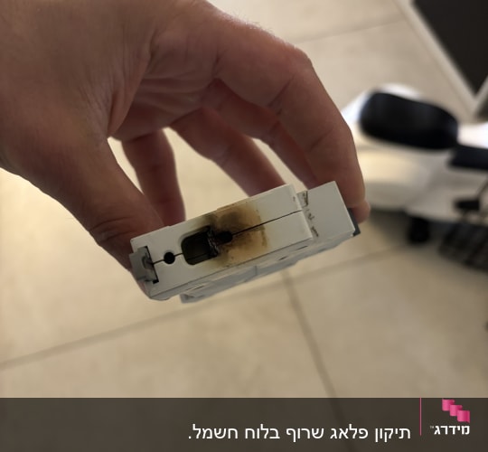 חלק חשמלי עם סימני שריפה מוחזק ביד